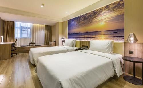 two beds in a hotel room with a painting on the wall at Atour Hotel Fuzhou Railway Station in Fuzhou