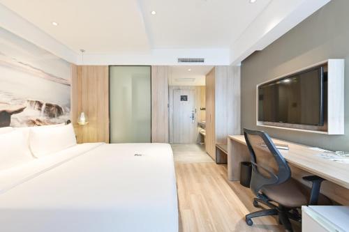 a hotel room with a bed and a desk and a tv at Atour Hotel Railway Station Dalian in Dalian