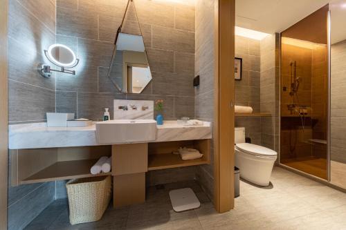 Atour Hotel Shenzhen Huaqiang North في شنجن: حمام مع حوض ومرحاض ومرآة