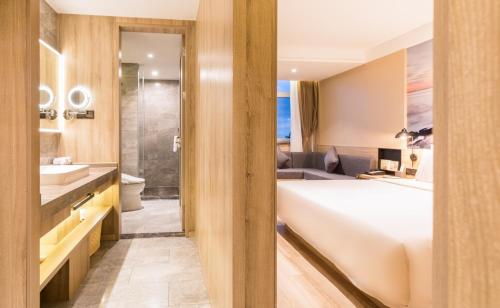 een badkamer met een bed, een wastafel en een bad bij Atour Hotel Weihai City Center in Weihai