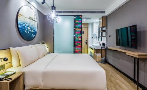 a bedroom with a large white bed and a sink at Atour Light Hotel Shandong Road CBD Qingdao in Qingdao