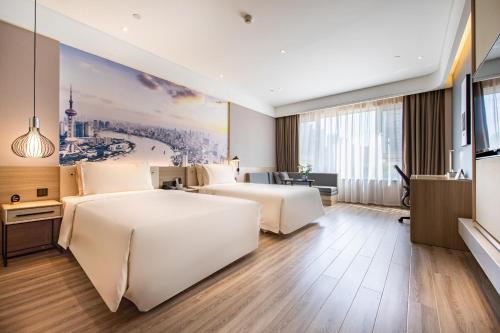 済南市にあるAtour Light Hotel Jinan International Covention Centreのベッド2台が備わる客室で、壁には絵画が飾られています。