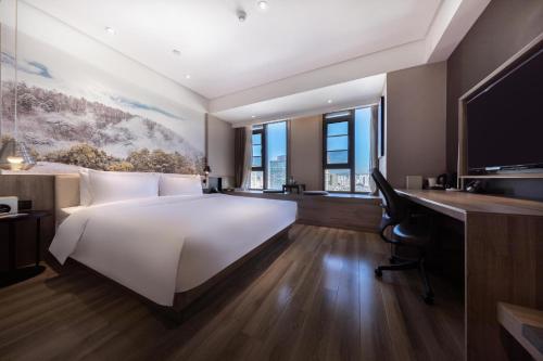 Schlafzimmer mit einem großen weißen Bett und einem Schreibtisch in der Unterkunft Atour Hotel Kunming Dianchi Lake in Kunming
