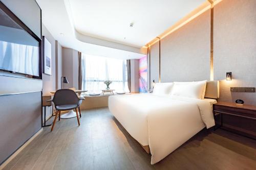 Atour Hotel Shenzhen Huaqiang North في شنجن: غرفة الفندق بسرير كبير ومكتب