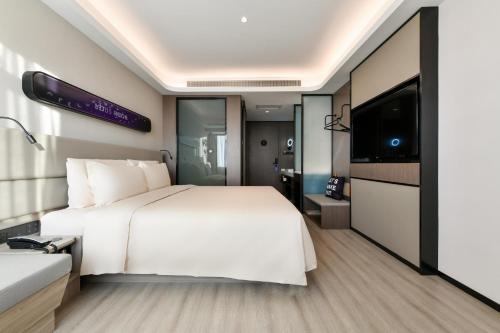 a bedroom with a white bed and a flat screen tv at Atour Light Hotel Shenyang High-Speed Railway Station in Shenyang