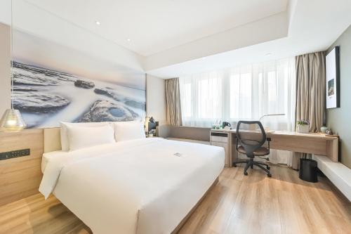 a hotel room with a large white bed and a desk at Atour Hotel Railway Station Dalian in Dalian