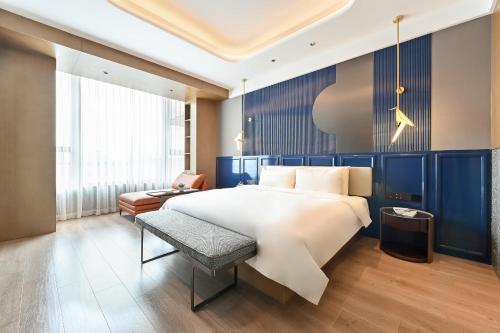 sypialnia z dużym białym łóżkiem i krzesłem w obiekcie Atour Hotel Beijing Hepingli UIBE w Pekinie