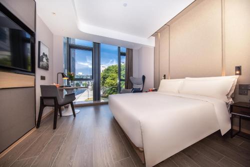 Schlafzimmer mit einem großen weißen Bett und einem Schreibtisch in der Unterkunft Atour Hotel Shanghai Wujiaochang Daxue Road in Shanghai