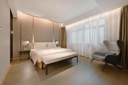 a bedroom with a large white bed and a chair at Atour Hotel Beijing Guomao Panjia Yuan in Beijing