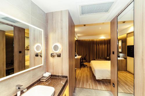 bagno con letto, lavandino e specchio di Atour Hotel Shanghai Pudong Airport a Shanghai