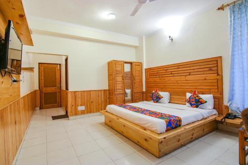 a bedroom with a large bed with a wooden headboard at FabHotel Greenwoods Inn in Dharamshala