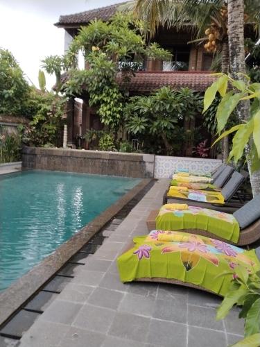 a pool with lounge chairs next to a house at Dewa Bungalows in Ubud
