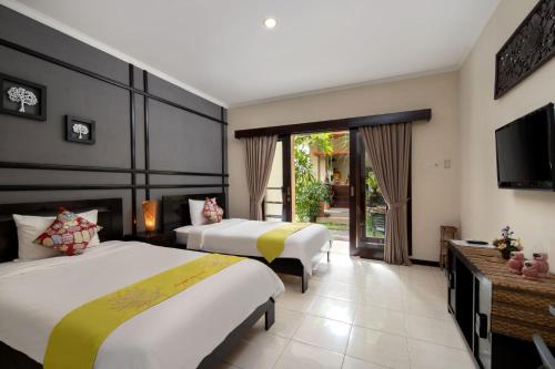 um quarto de hotel com duas camas e uma televisão em Canggu Bona Kubu em Canggu
