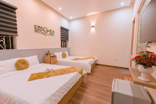 two beds in a room with white walls and wooden floors at Golden Diamond Hotel in Hanoi