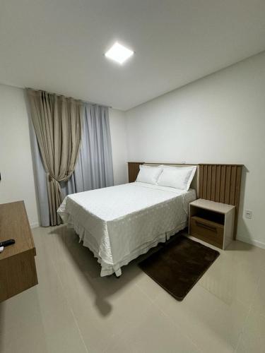 une chambre avec un lit blanc et une fenêtre dans l'établissement Apartamento à 390m do Mar, à Itapema