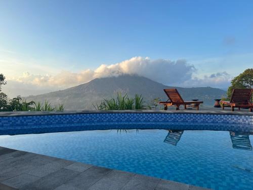 a pool with two chairs and a mountain in the background at Pinggan Cliff in Baturaja
