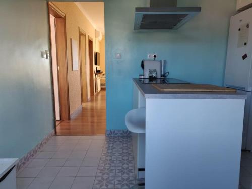 a blue kitchen with a counter and a hallway at CasaFamiliar/Tranquilidad25minBCN/BbqPiscinaAAWifi in Rubí