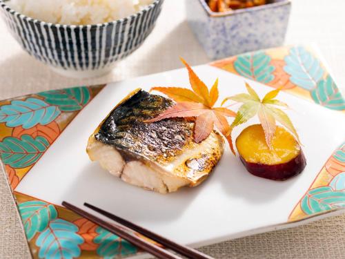 a plate with a piece of fish and an orange slice at Miyakonojo Green Hotel in Miyakonozyō