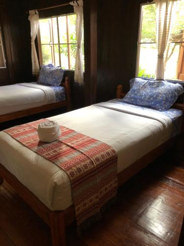 twee bedden in een kamer met twee ramen bij Lampang homestay2 in Lampang