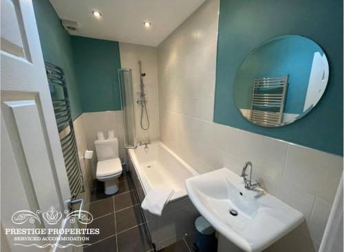 uma casa de banho com um lavatório, uma banheira e um espelho. em Apartment 1 West County by Prestige Properties SA em Millom