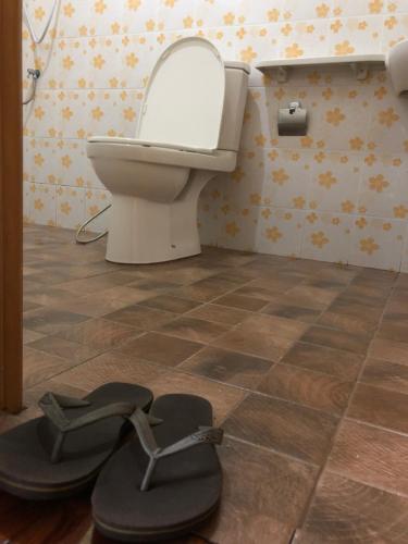ein Badezimmer mit einem WC und einem Paar Sandalen in der Unterkunft Lampang homestay2 in Lampang