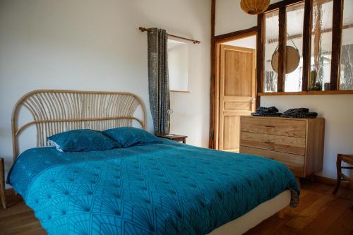 a bedroom with a blue bed and a wooden dresser at La tête dans les nuages et les pieds dans l'eau in Saint-Benoît-en-Diois