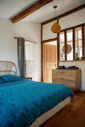 - une chambre avec un lit bleu et une commode en bois dans l'établissement La tête dans les nuages et les pieds dans l'eau, à Saint-Benoît-en-Diois