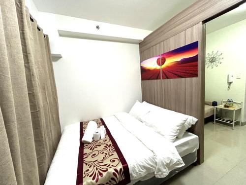 a bedroom with a bed with a painting on the wall at Shore Residences MOA Dynastel Staycation in Manila