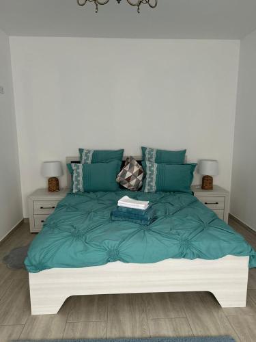 a bed with a green comforter and two night stands at Studio G&A Hunedoara Apartment in Hunedoara