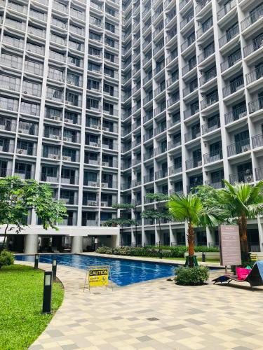a large building with a swimming pool in front of it at Shore Residences MOA Dynastel Staycation in Manila