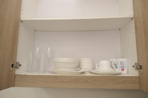 a cabinet with plates and cups on a shelf at Shore Residences MOA Dynastel Staycation in Manila