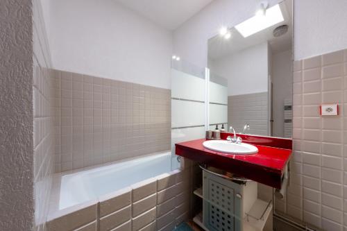 uma casa de banho com um lavatório vermelho e um espelho. em Le Cocon- Atypique WIFI Parking Services ProsConciergerie Comte des Cierges em Gien