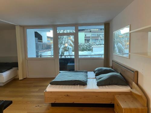 Bett in einem Zimmer mit zwei großen Fenstern in der Unterkunft Apartment Herzog Kaprun in Kaprun