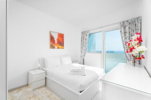 a white bedroom with a bed and a window at Nasma Luxury Stays - Serenity by the Sea 1BR Apartment With Beach Views in Abu Dhabi