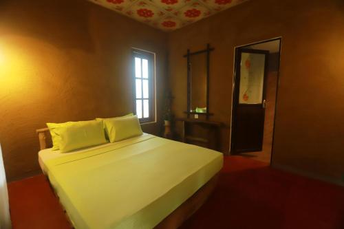 a bedroom with a bed with white sheets and a window at Dinna Nature Hostel in Sigiriya