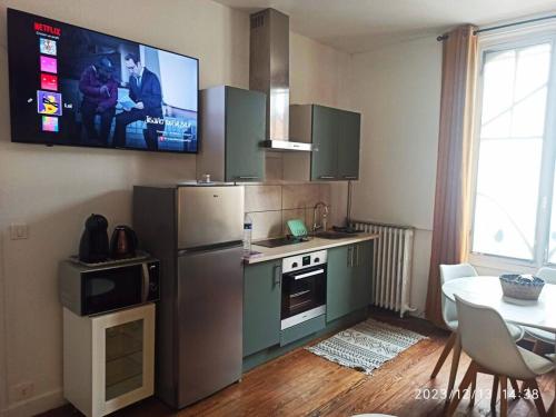 a kitchen with a refrigerator and a table and a tv at appartement dans une meulière d'architecte in Provins