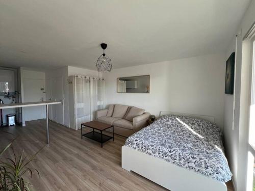 een witte slaapkamer met een bed en een bank bij Studio 35m2, 500m de la plage + parking gratuit. in Six-Fours-les-Plages