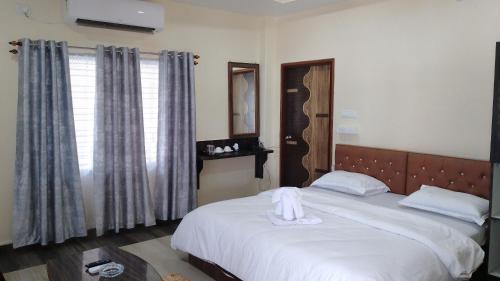 Whistling Wind Resorts by StayApart في لاتاغري: غرفة نوم بسرير وملاءات بيضاء ونافذة