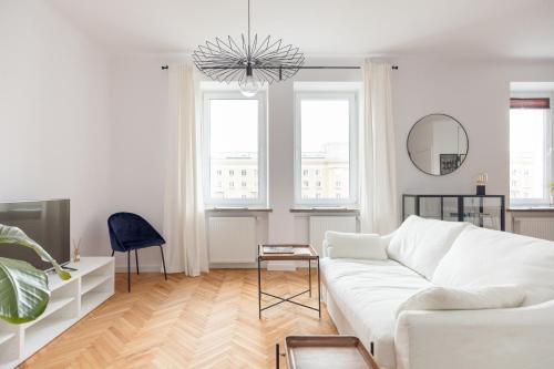 een witte woonkamer met een witte bank en 2 ramen bij Designer Apartment in the Central Warsaw in Warschau