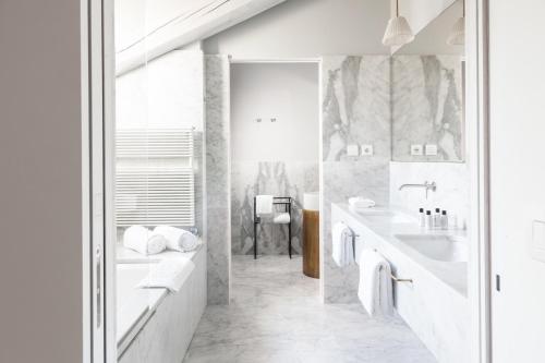a white bathroom with a tub and a sink at Senato Hotel Milano in Milan