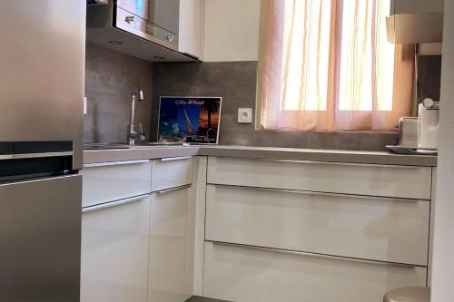 une cuisine avec des armoires blanches et une fenêtre dans l'établissement St Raphaël centre calme clim mer commerces à pieds, à Saint-Raphaël