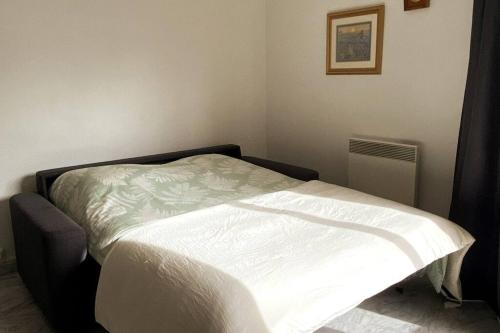 Ce lit se trouve dans une chambre dotée d'un couvre-lit blanc. dans l'établissement St Raphaël centre calme clim mer commerces à pieds, à Saint-Raphaël