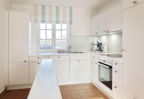uma cozinha branca com armários brancos e uma janela em Achter Duenem App 1 em Wenningstedt