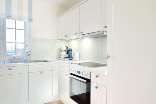 uma cozinha branca com armários brancos e um fogão em Achter Duenem App 1 em Wenningstedt