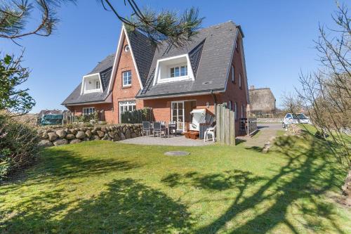 a brown house with a black roof and a yard at Fewo Arnfried Whg 5 in Wenningstedt