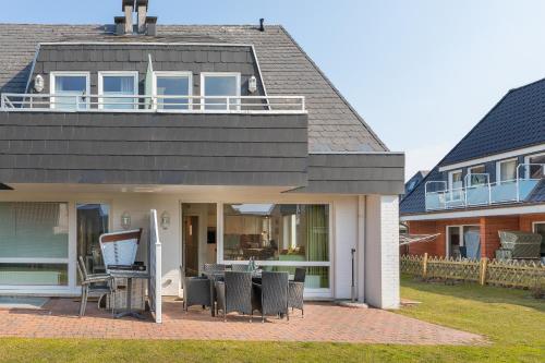 a house with chairs on a patio in front of it at Haus Sonnenschein Whg H in Wenningstedt