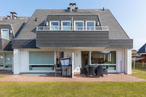 a house with a balcony and a table and chairs at Haus Sonnenschein Whg H in Wenningstedt