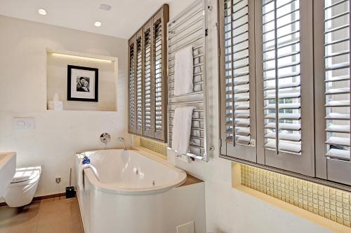 a bathroom with a tub and a toilet and a sink at SYLThouse in Wenningstedt