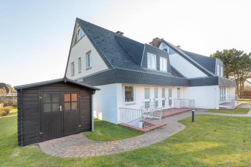 uma grande casa branca com um telhado preto em Haus Sonnenschein Whg G em Wenningstedt