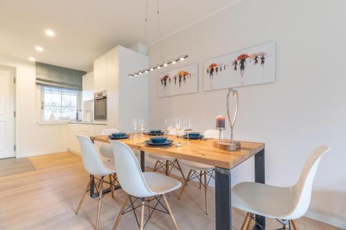 a dining room with a wooden table and white chairs at Ameland App 4 in Wenningstedt